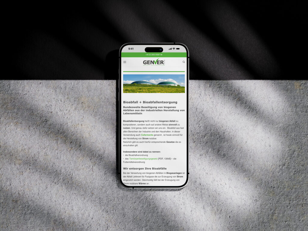 Ein Smartphone, auf dem die GENVER-Website über die Entsorgung von Bioabfall angezeigt wird, liegt auf einer hellgrauen, strukturierten Oberfläche, wobei die Schatten der Jalousien diagonal über die Szene geworfen werden.