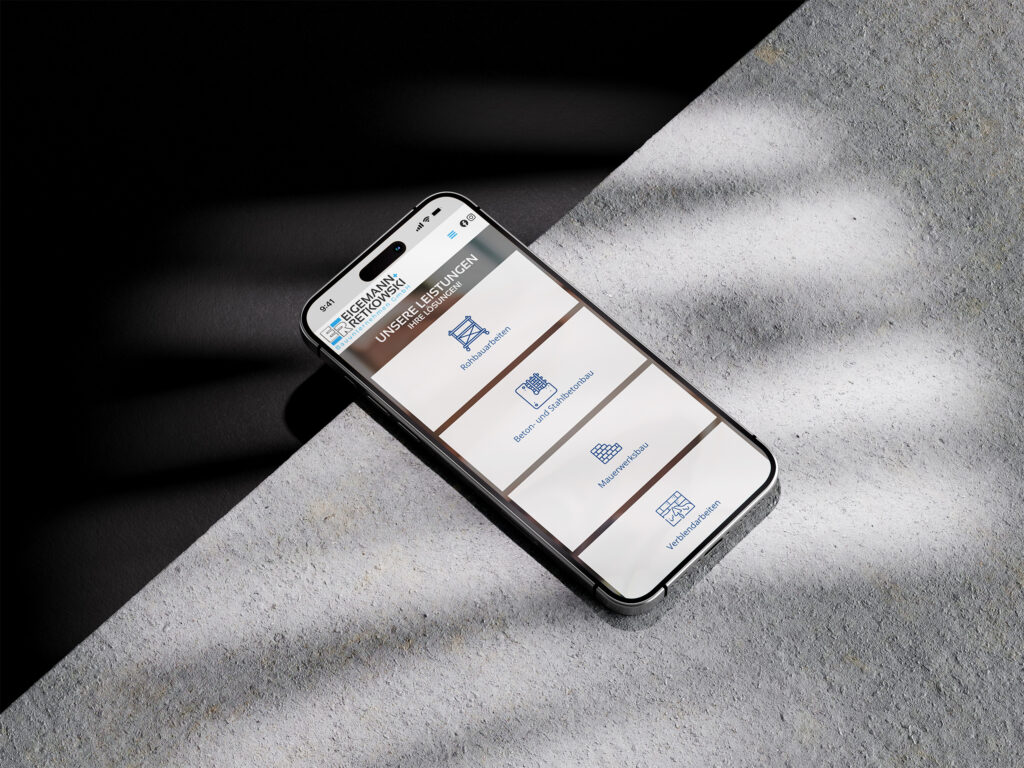 Auf einer strukturierten Oberfläche liegt ein Smartphone, das eine deutschsprachige App mit Icons für verschiedene Dienste anzeigt, teilweise beleuchtet von schrägem Sonnenlicht - eine Eigemann + Retkowski Website Referenz.