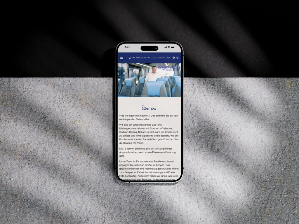 Ein Smartphone, das auf einer strukturierten Oberfläche liegt, zeigt die Website von Fragemanns Reisekutsche mit einem Bild von Menschen, die in einem Bus sitzen, und einem deutschen Text unter dem Abschnitt mit der Überschrift Über uns. Schatten und Licht fallen auf den Hintergrund.