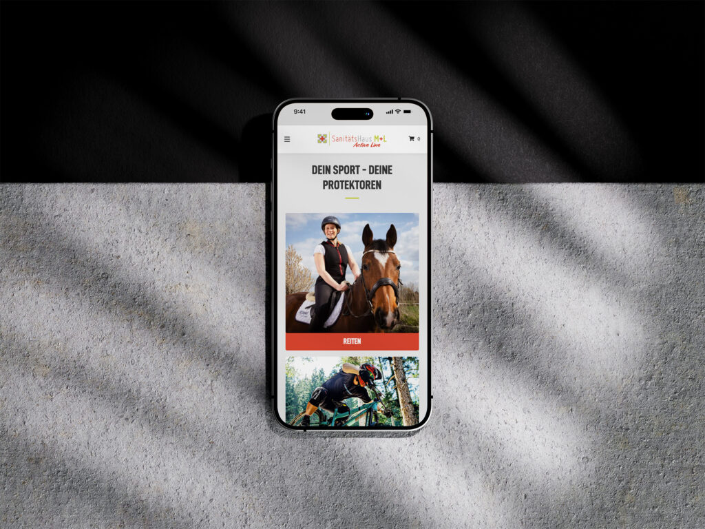 Ein Smartphone zeigt die Website des Sanitätshauses M+L Online-Shop mit den Bildern eines behelmten Reiters und eines Radfahrers in Schutzkleidung, darüber ein deutscher Text und im Hintergrund Schattenwurf auf einer Betonfläche.