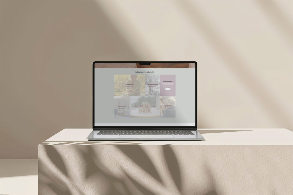 Ein Laptop steht auf einer beigen, strukturierten Tischdecke in sanftem Tageslicht und zeigt die Heike Holdschlag Website mit gedämpften Farben und Bildern vor einem neutralen, minimalistischen Hintergrund.