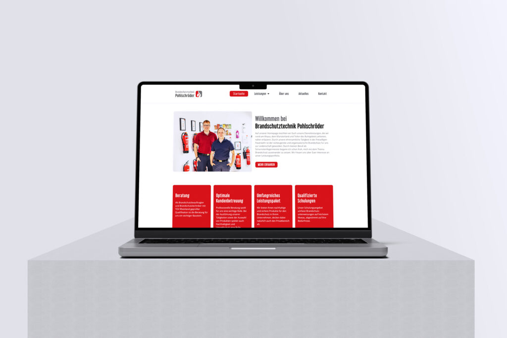 Ein Laptop auf einer hellgrauen Plattform zeigt die Website von Brandschutztechnik Pohlschröder mit zwei Personen, Feuerlöschern und roten Infokästen über Brandschutzdienstleistungen.