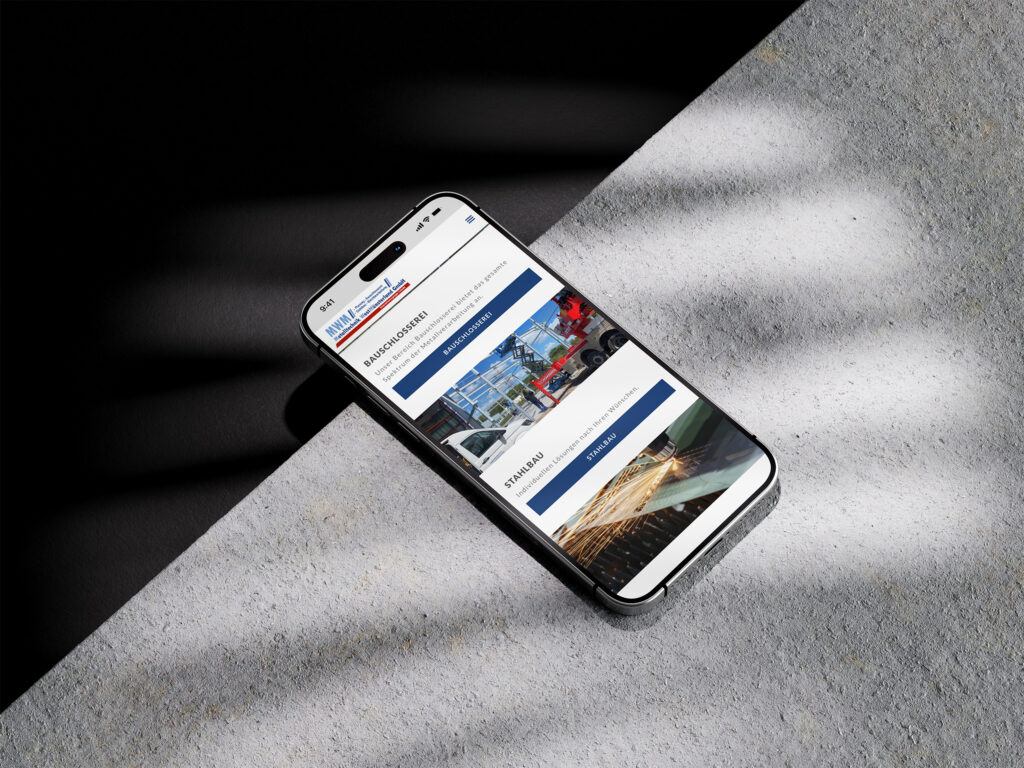 Ein Smartphone liegt auf einer hellen, strukturierten Oberfläche und zeigt die Website der MWM Metalltechnik Westmünsterland an, auf der Bilder von Lastwagen, Gebäuden und Baumaterialien gezeigt werden. Das Sonnenlicht wirft Schatten auf die Szene.