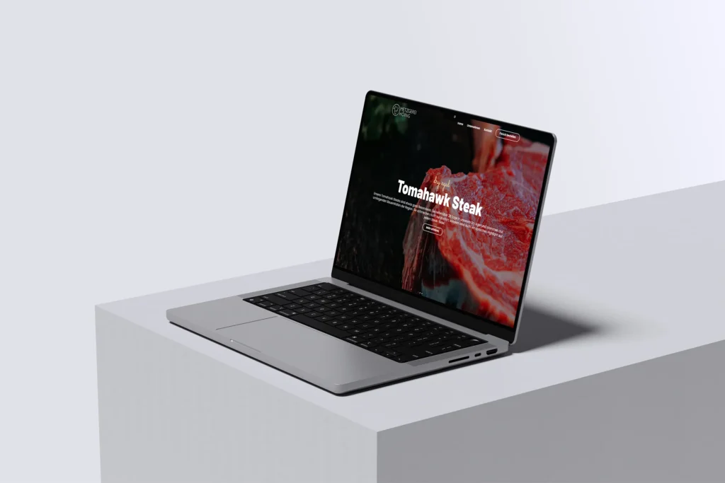Ein silberner Laptop auf weißer Oberfläche zeigt die Metzgerei Höing Website Referenz mit einem großen Bild eines Tomahawk Steaks mit dem Text Tomahawk Steak und einem sichtbaren Navigationsmenü auf dem Bildschirm.