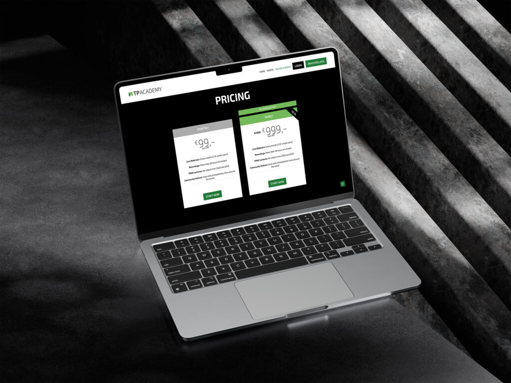 Ein Laptop auf einer dunklen Betonfläche zeigt die Preisseite der TP Academy mit zwei Abonnementplänen, deren Preise und Funktionen in weißer und grüner Schrift auf dem Bildschirm aufgeführt sind.