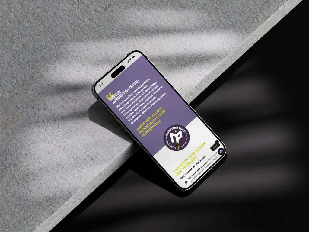 Ein Smartphone auf einer grauen Steinoberfläche zeigt eine violette und graue Webseite mit weißem und gelbem Text und einem kreisförmigen Logo am unteren Rand an. Das Sonnenlicht erzeugt Schattenmuster auf dem Telefon und der Oberfläche.