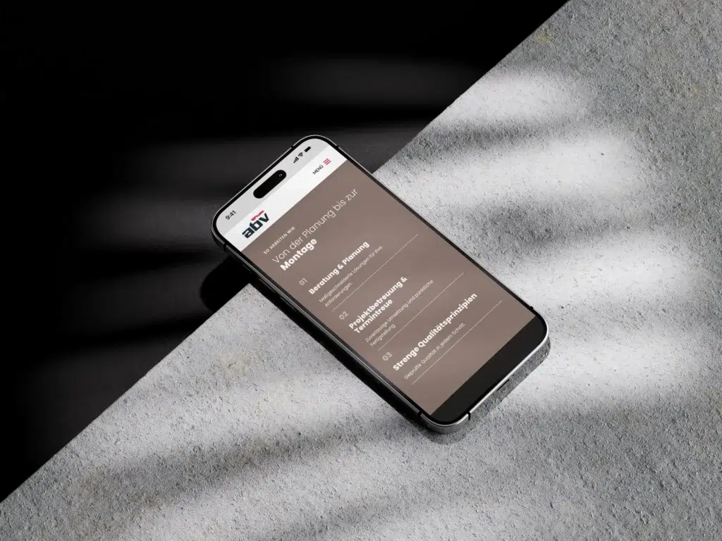 Ein Smartphone, auf dessen Bildschirm eine Webseite mit braunem Hintergrund zu sehen ist, liegt auf einer strukturierten Oberfläche, teilweise im Schatten und teilweise von Sonnenlicht beleuchtet. Auf dem Bildschirm des Smartphones ist Text auf Bulgarisch zu sehen, und oben ist das Logo „abv“ zu erkennen.