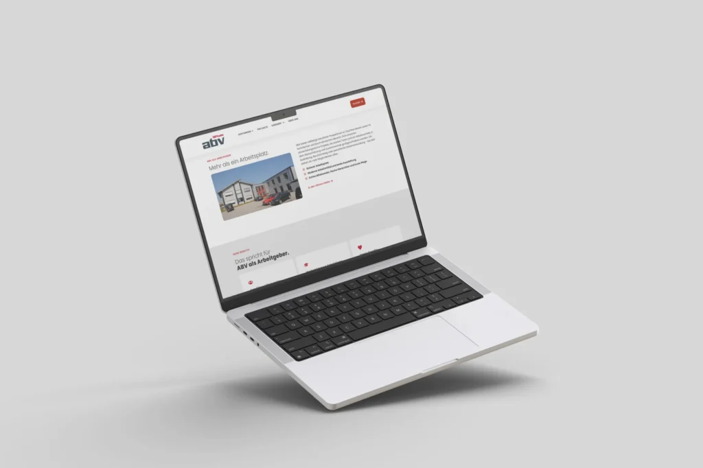 Ein silberner Laptop schwebt vor einem hellgrauen Hintergrund; auf seinem Bildschirm ist eine Website mit dem Bild eines Gebäudes, Text und einer roten Schaltfläche zu sehen. Die Tastatur ist schwarz, und das Gerät ist leicht nach rechts geneigt.