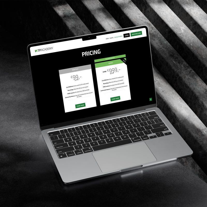 Ein Laptop auf einer dunklen Betonfläche zeigt die Preisseite der TP Academy mit zwei Abonnementplänen, deren Preise und Funktionen in weißer und grüner Schrift auf dem Bildschirm aufgeführt sind.